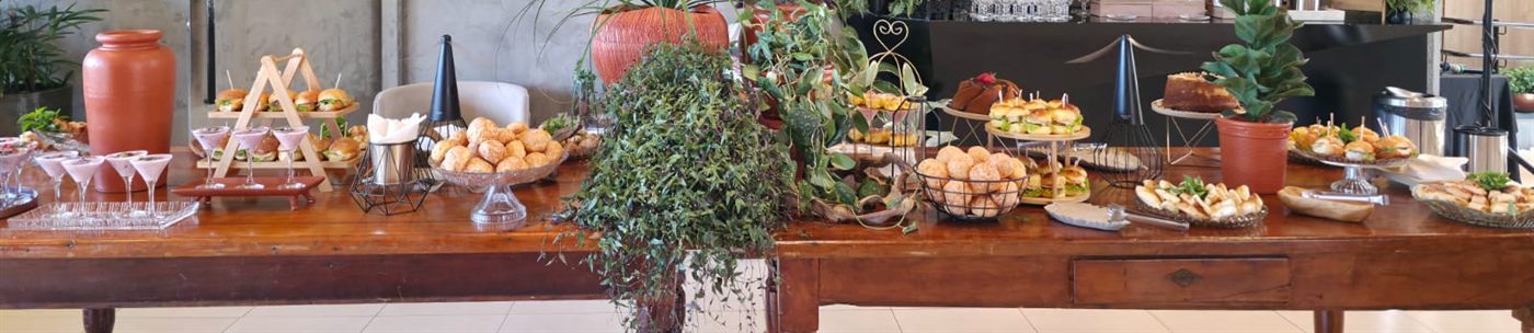 Mesa de coffee longa com plantas, pães e mini sanduíches