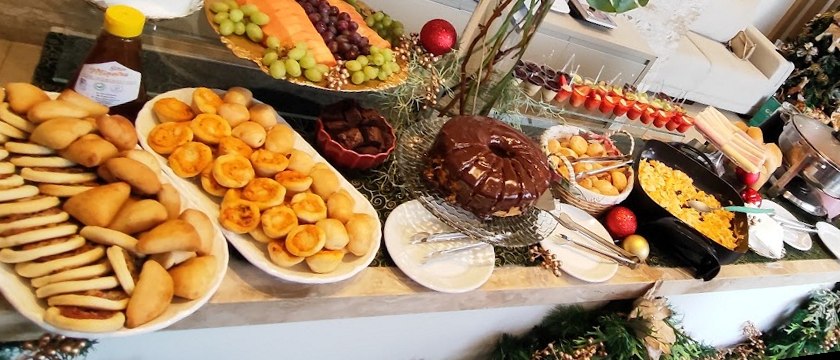 Mesa de café da manhã de Natal com salgados assados, frutas, bolo e espetinhos