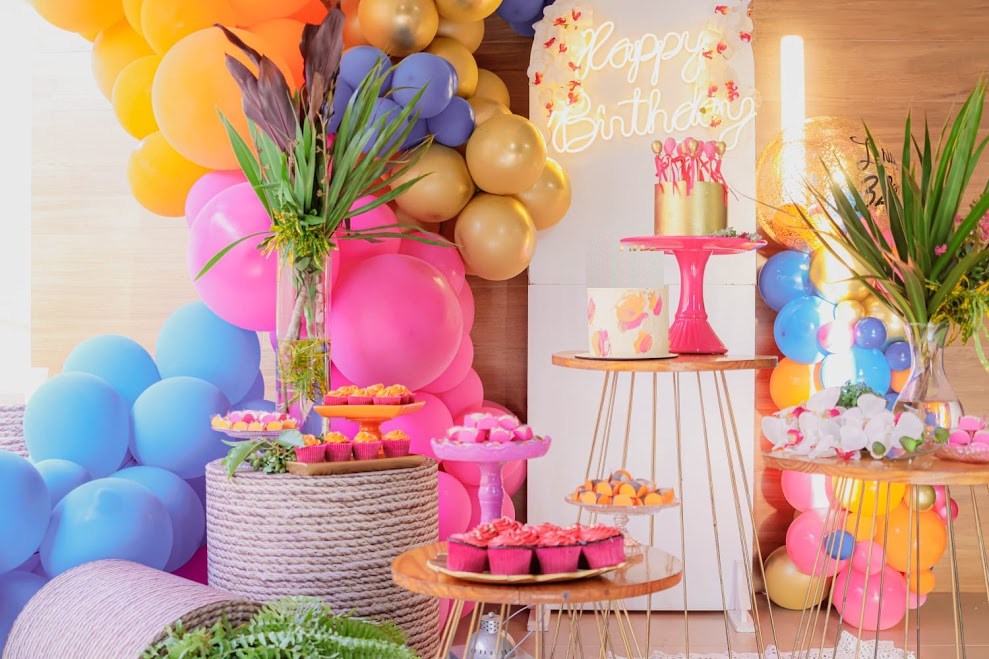 Mesa de aniversário com bolos, doces e arco de balões