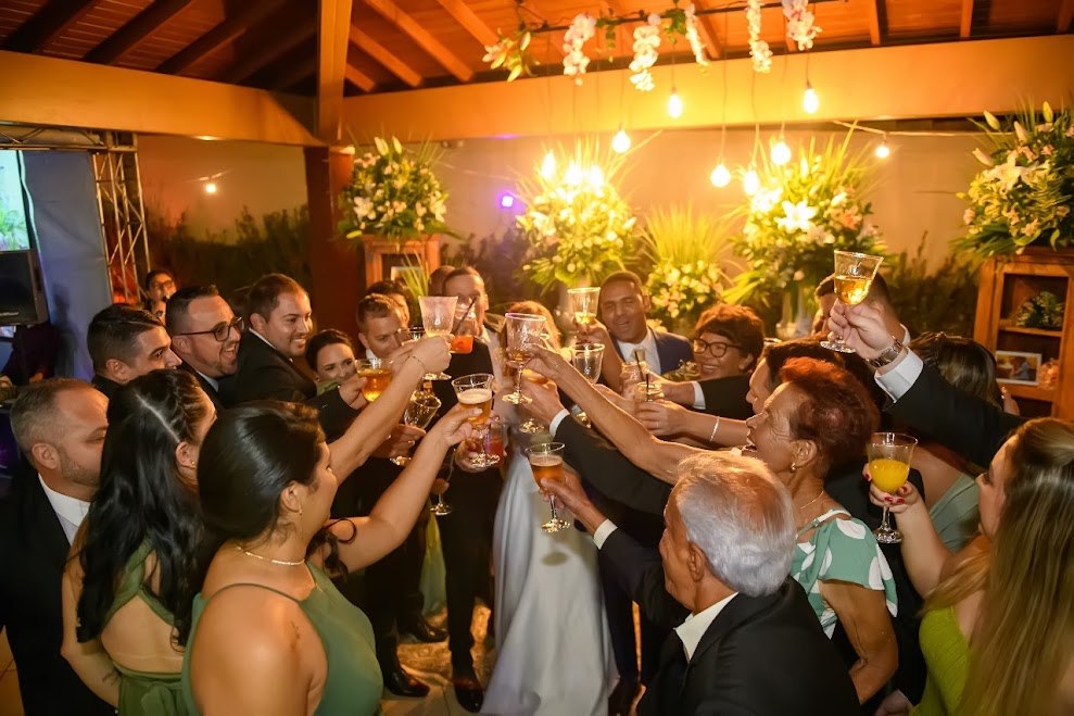 Convidados erguendo as taças em um brinde com os noivos
